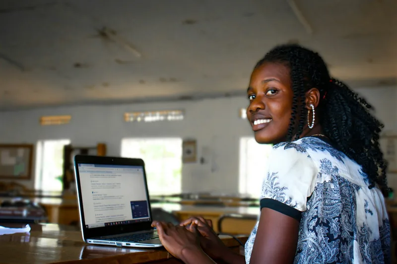 A young woman working on a laptop in a classroom