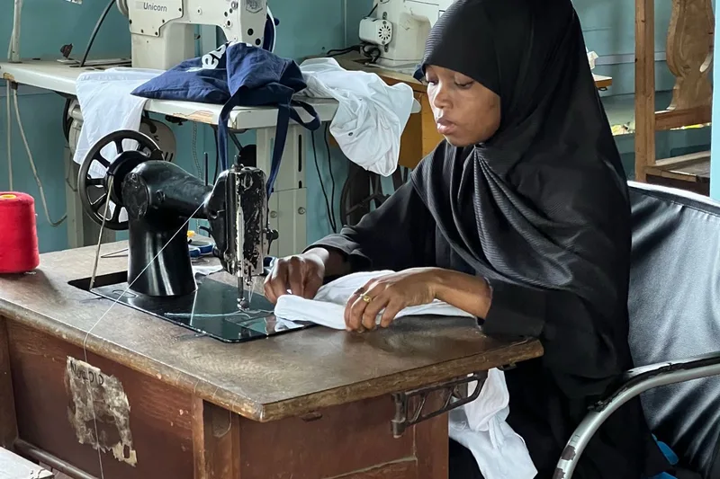 A young woman sewing at a machine in the LongSan workshop